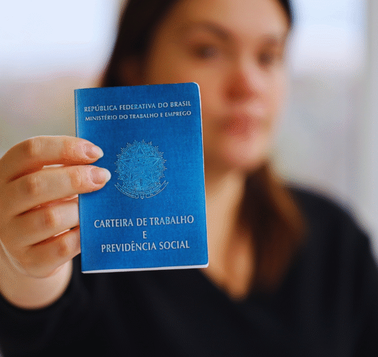 Uma pessoa segura uma Carteira de Trabalho e Previdência Social brasileira em direção à câmera, destacando as recentes melhorias no FGTS para os trabalhadores.