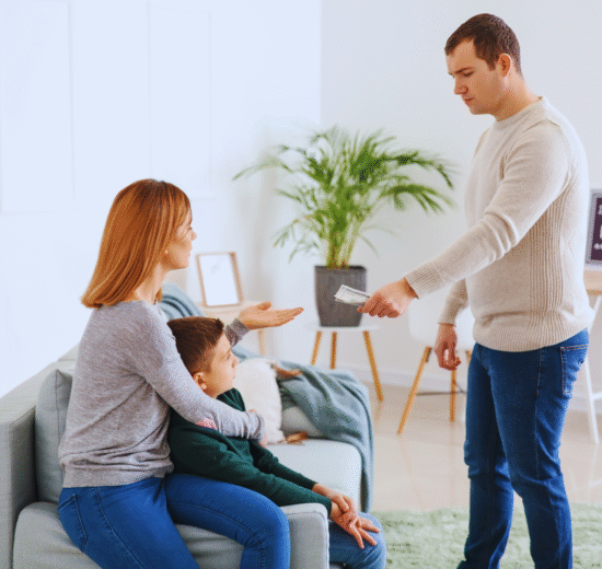 Um homem entrega dinheiro a uma mulher sentada que está com uma criança em uma sala de estar, ilustrando o pagamento da pensão alimentícia retroativa.