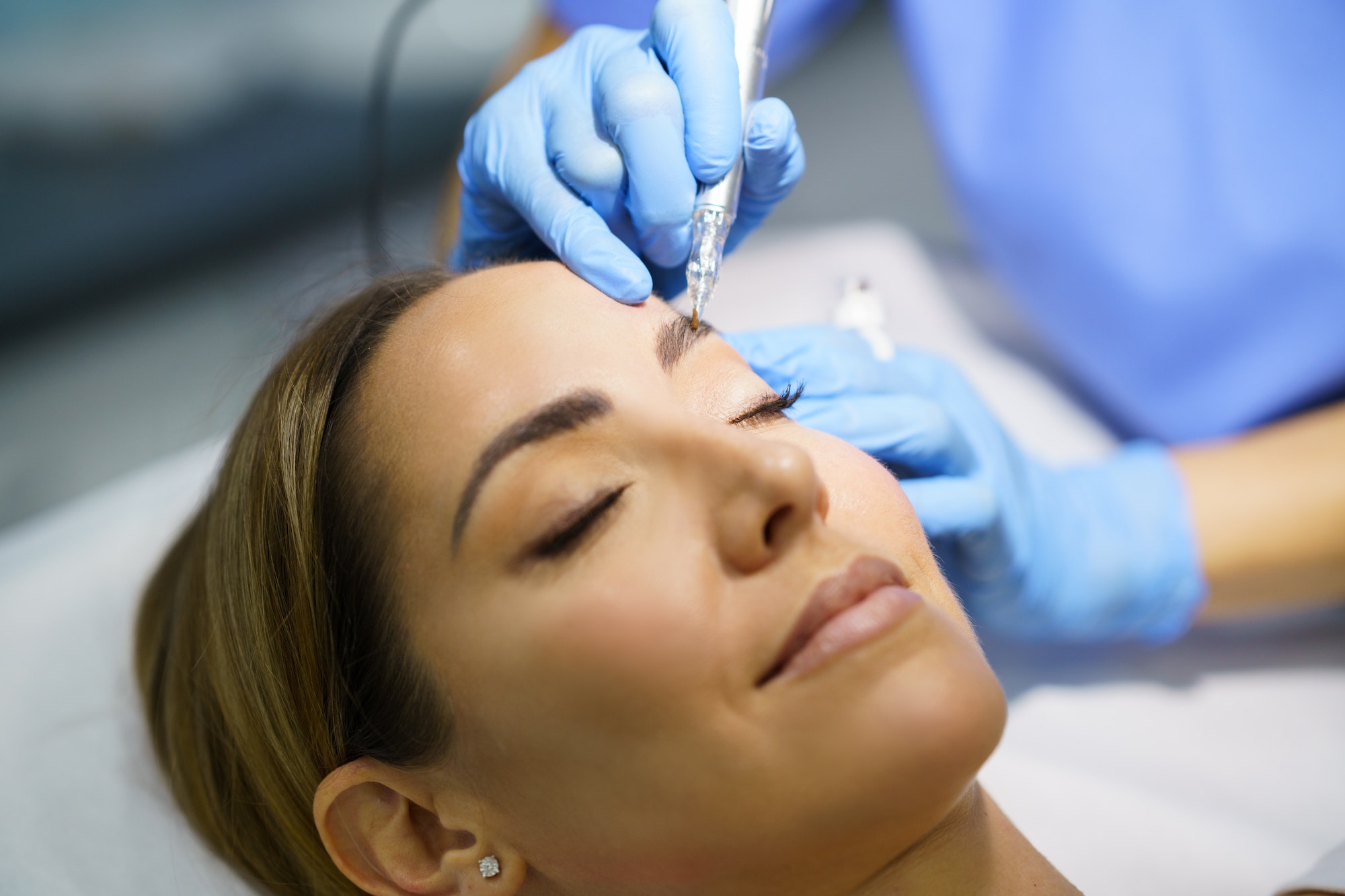Permanent make-up for eyebrows of beautiful woman in a beauty salon. Micropigmentation treatment.